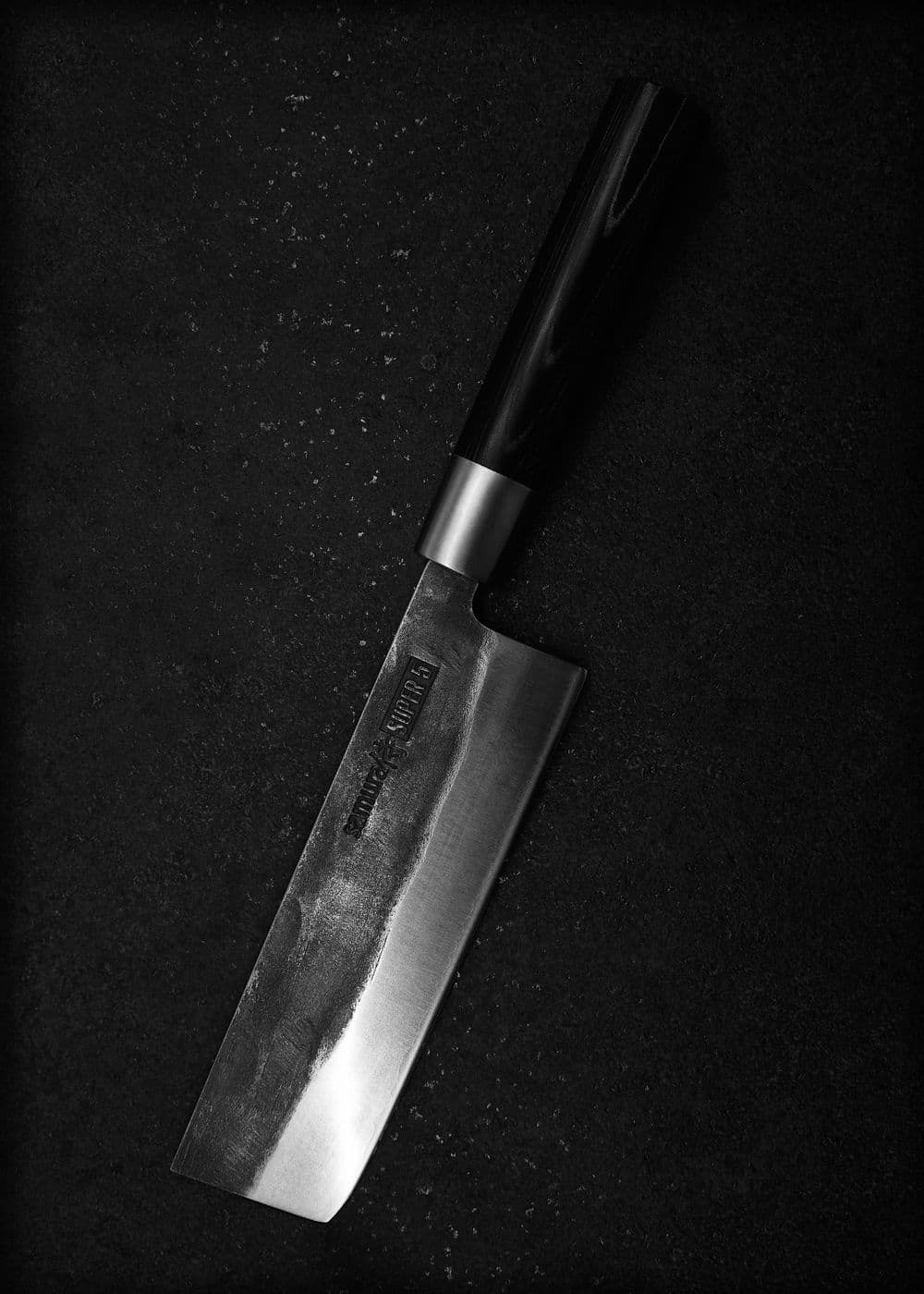 A santoku-style Japanese vegetable knife with a dark forged blade and wooden handle
