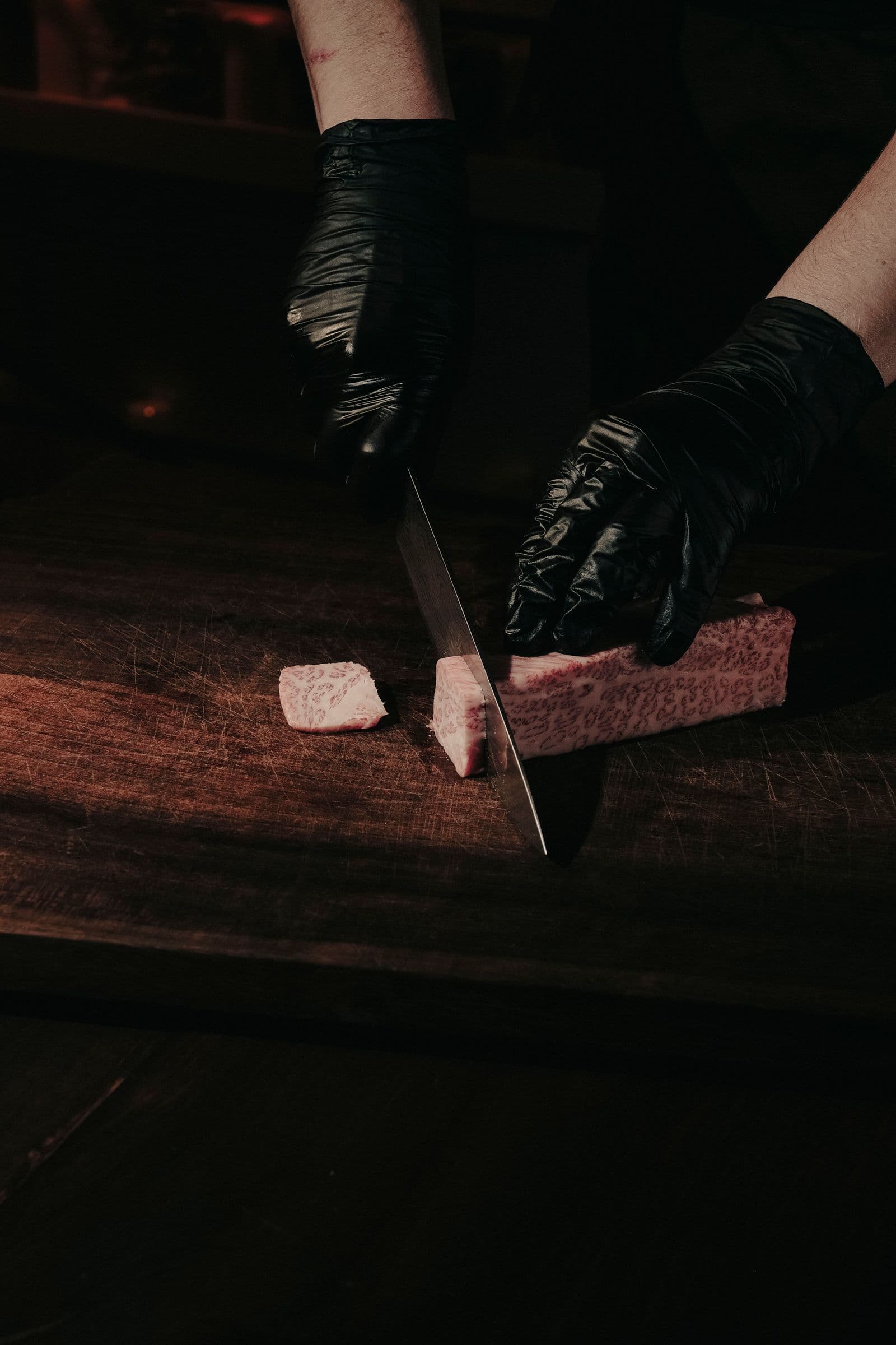 Slicing a block of marbled wagyu with a long Japanese slicer on a wooden board