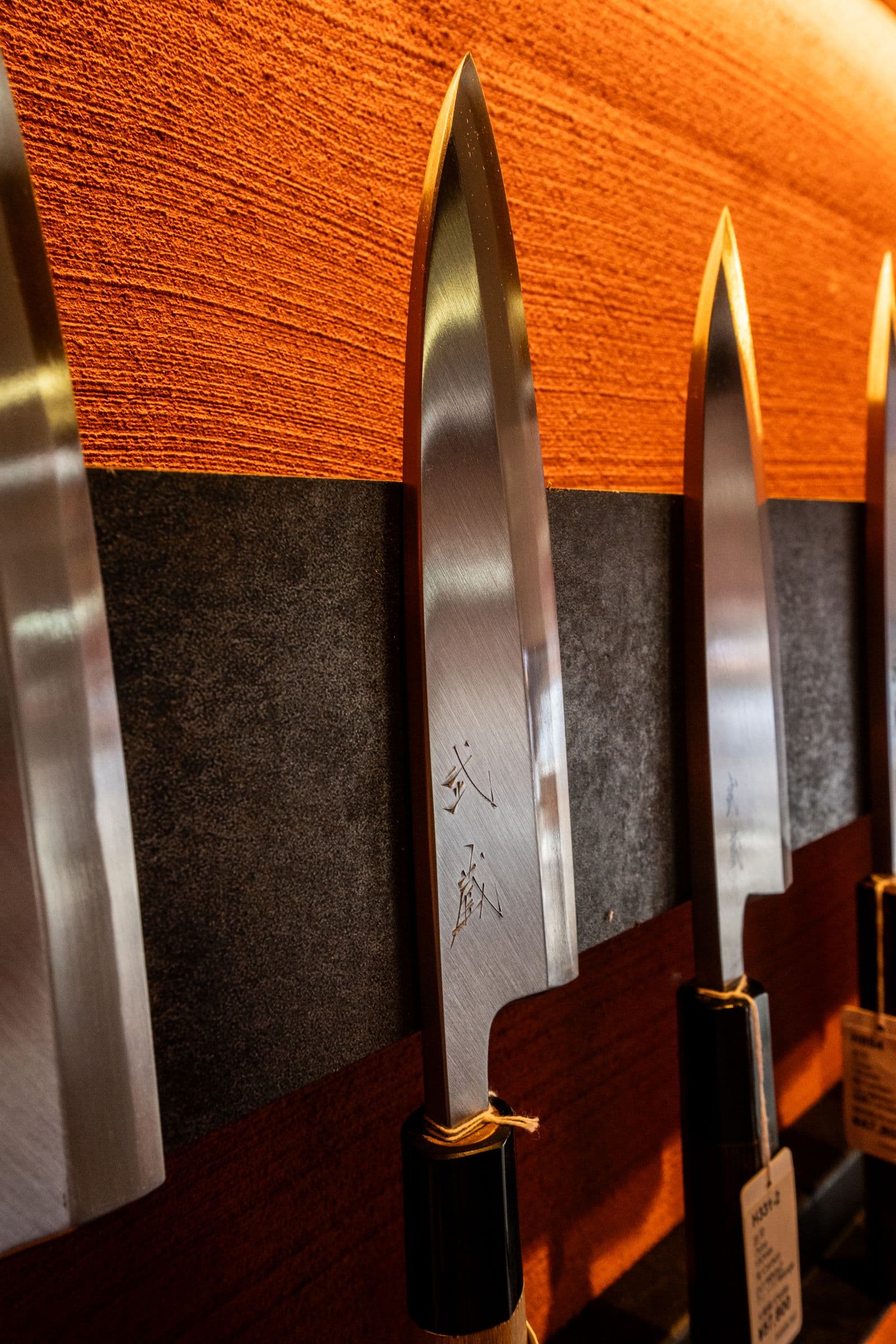 A close-up of single-bevel Japanese slicing knives with makers' marks
